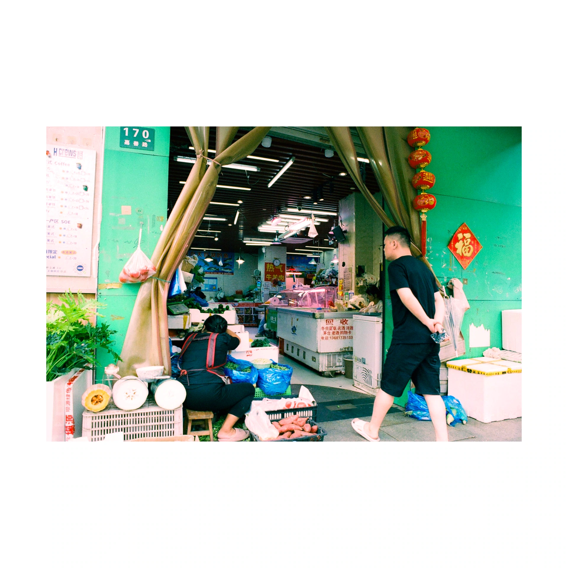 Person passing a green shop with bamboo poles