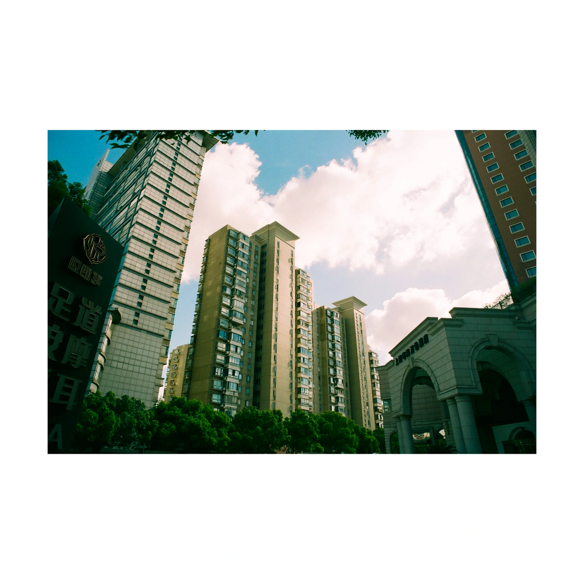 Tall buildings framing a blue sky with clouds