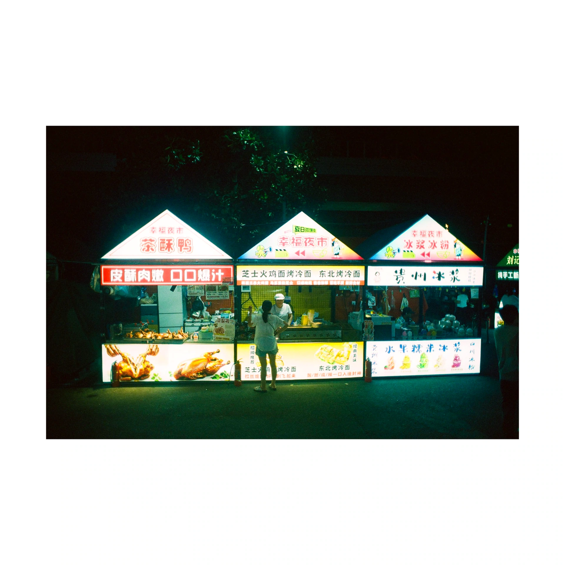 Three brightly lit food stalls at night