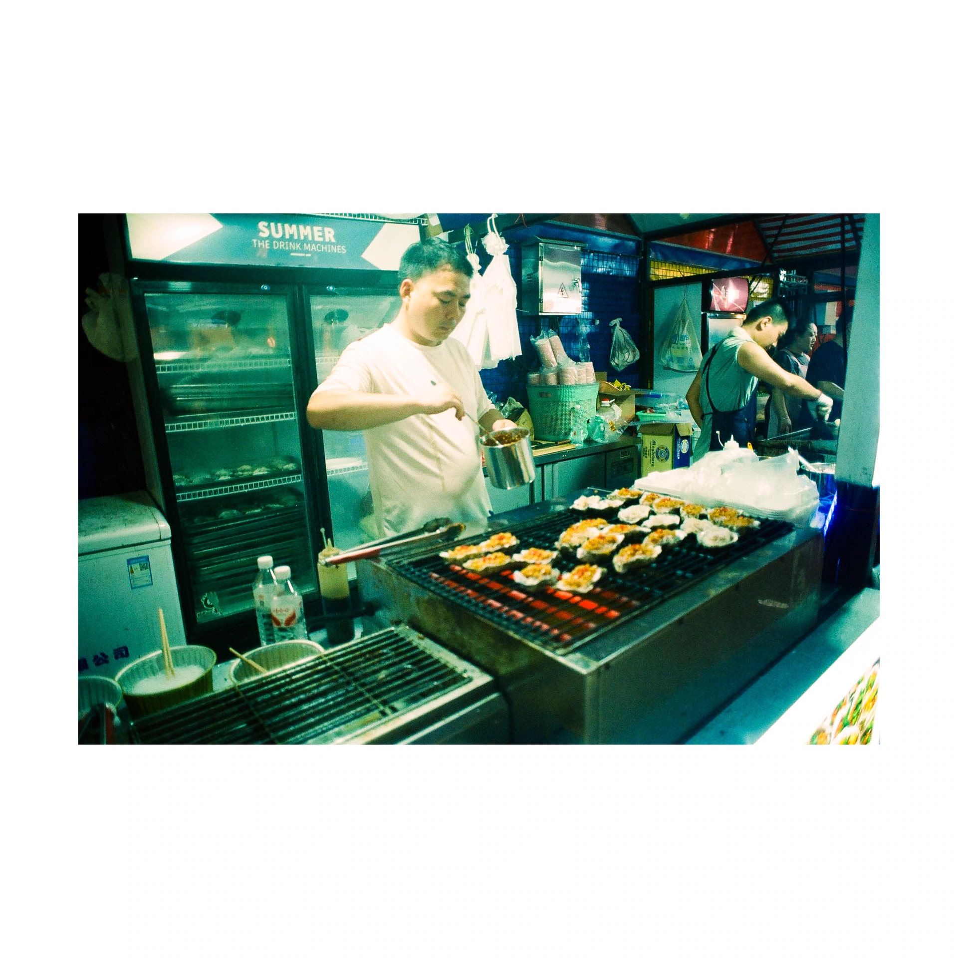 Person preparing skewers on a grill at a food stall