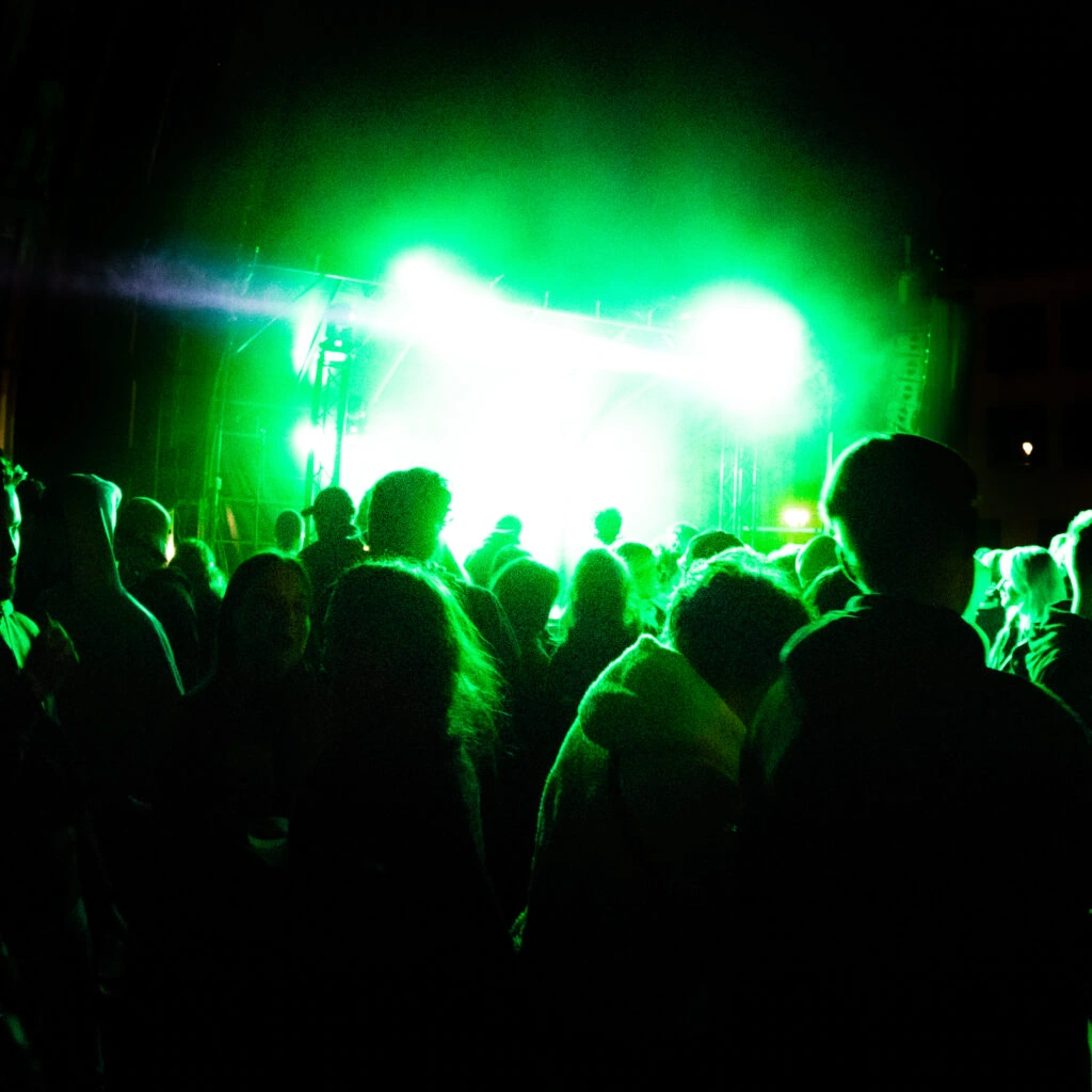Audience silhouettes facing a stage lit in green