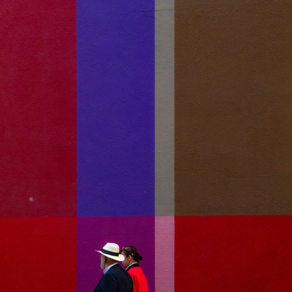 Passers-by in front of a wall of coloured bands