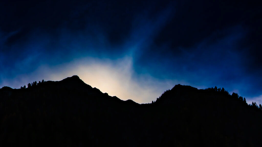 Mountain silhouettes beneath a dark blue sky