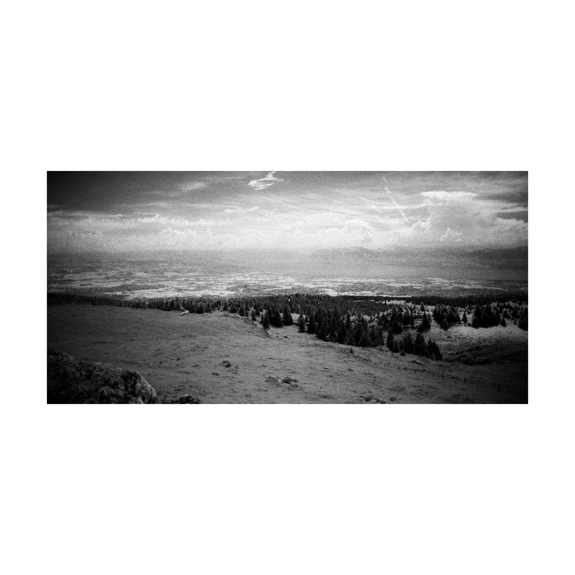 Panoramic infrared view of a valley beneath a streaked sky