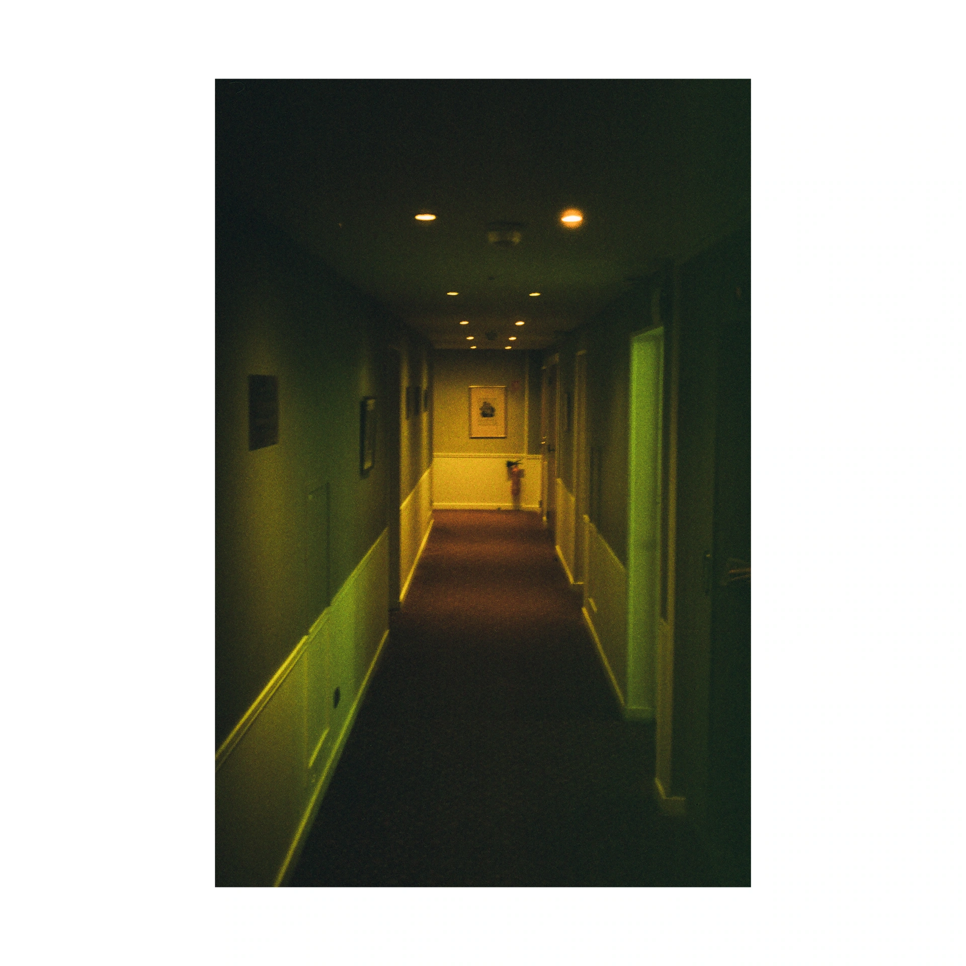 Long dark corridor lit by ceiling lamps