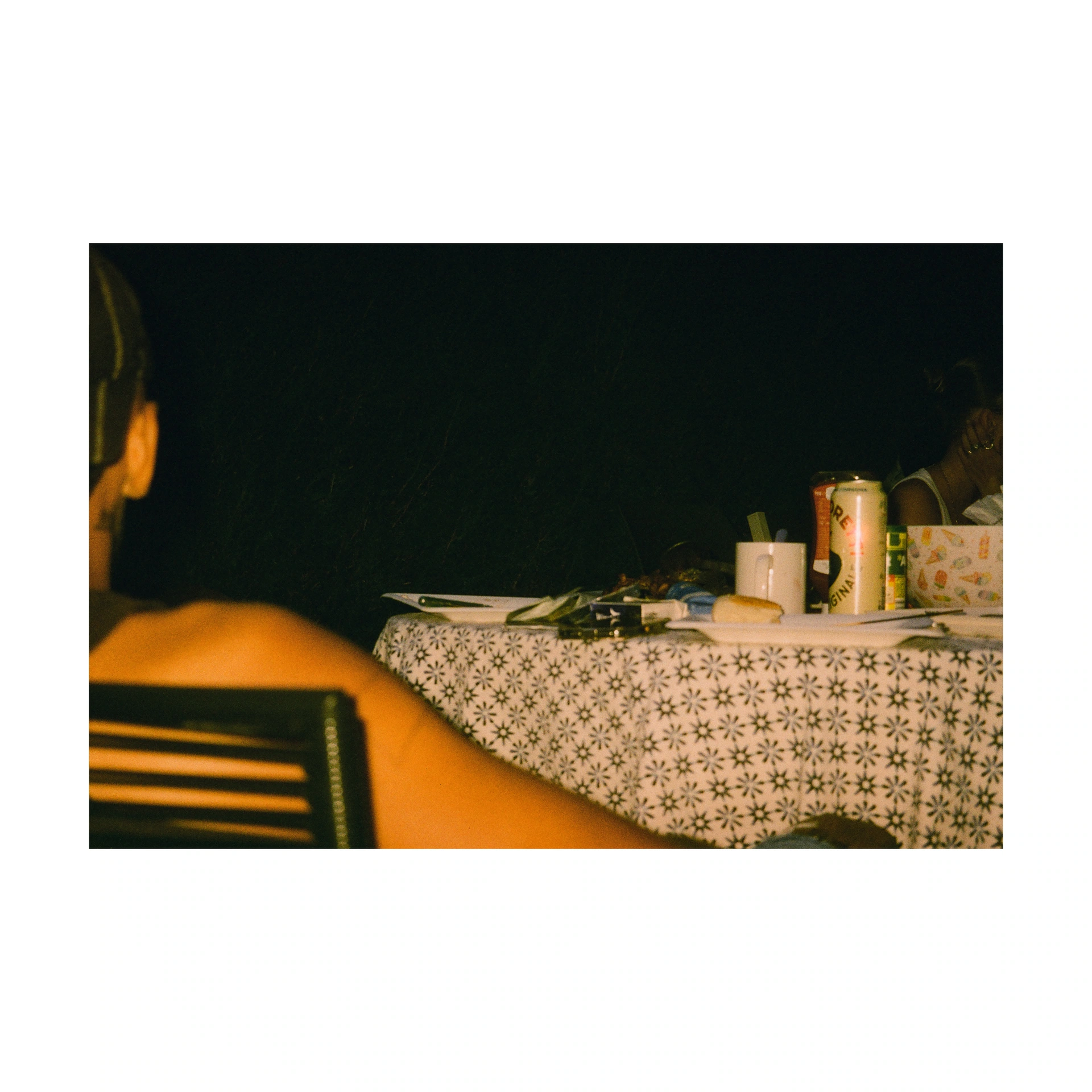 Person seated at a patterned tablecloth with drinks