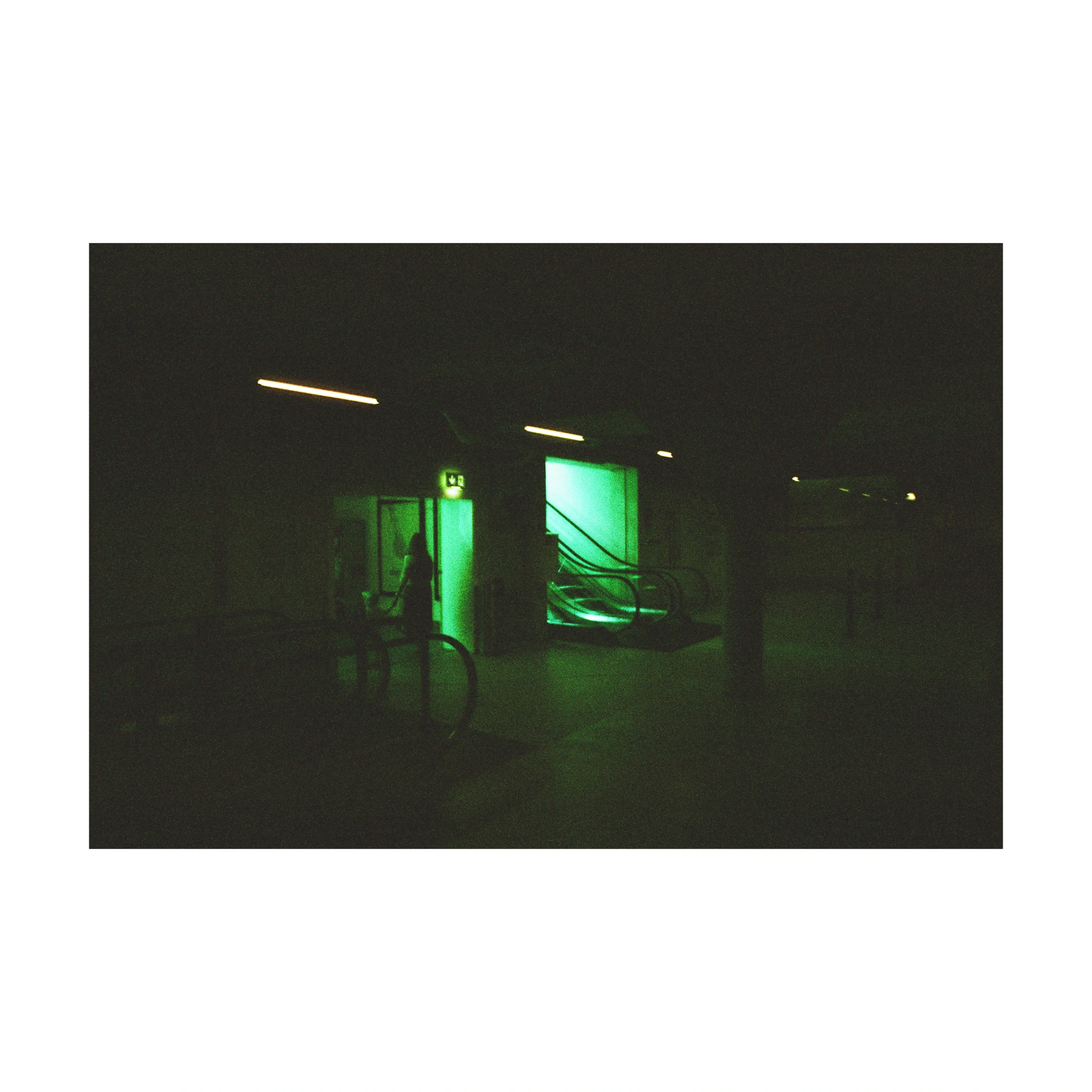 Night-time street scene around a green-lit entrance