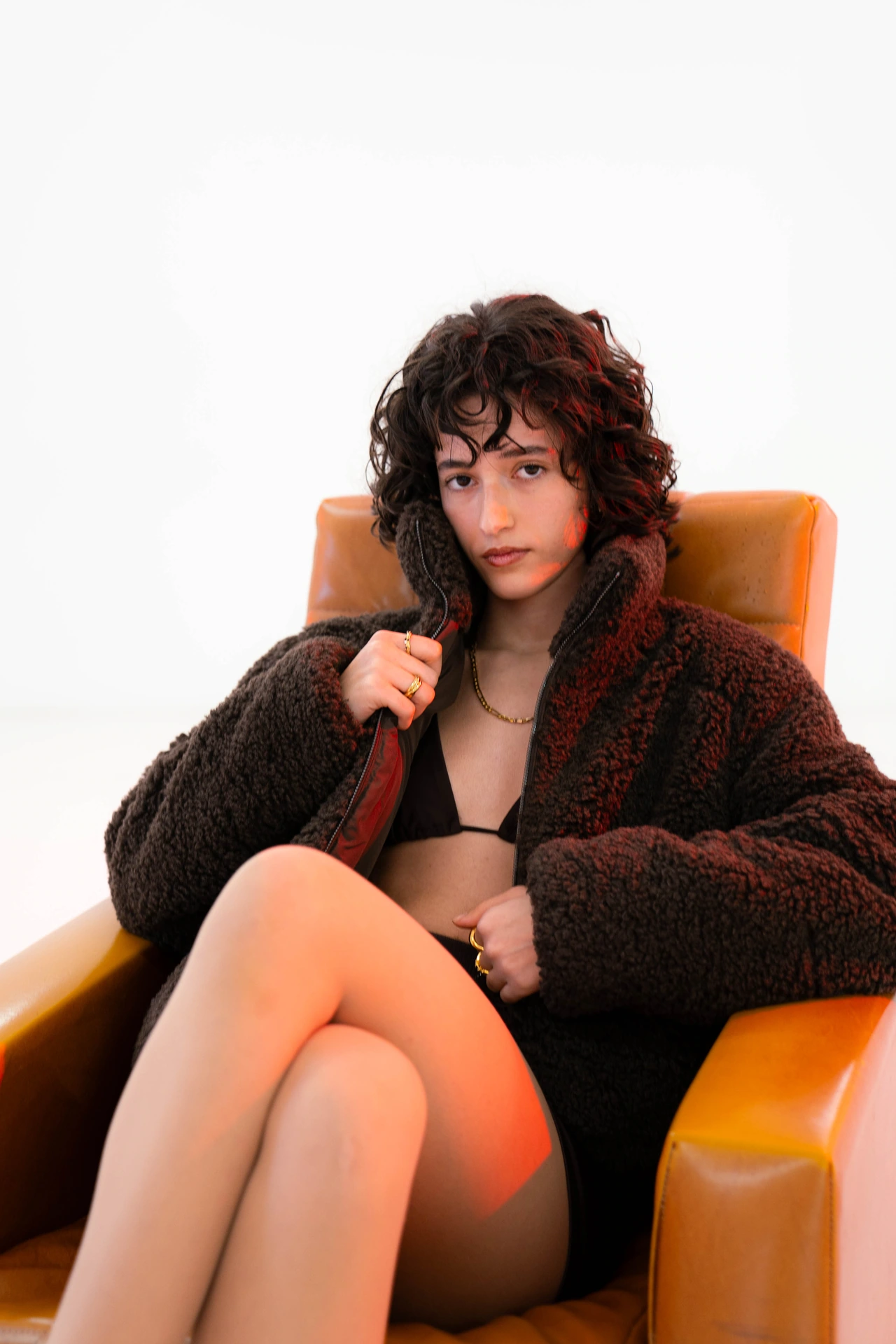 Portrait of Diana in an orange armchair against white
