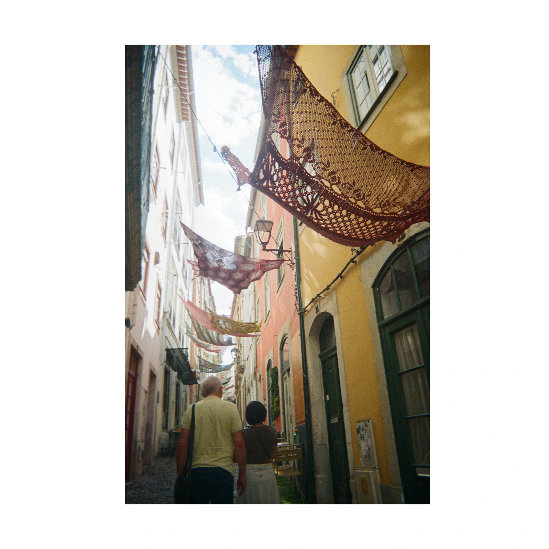 People in a narrow alley beneath net decorations