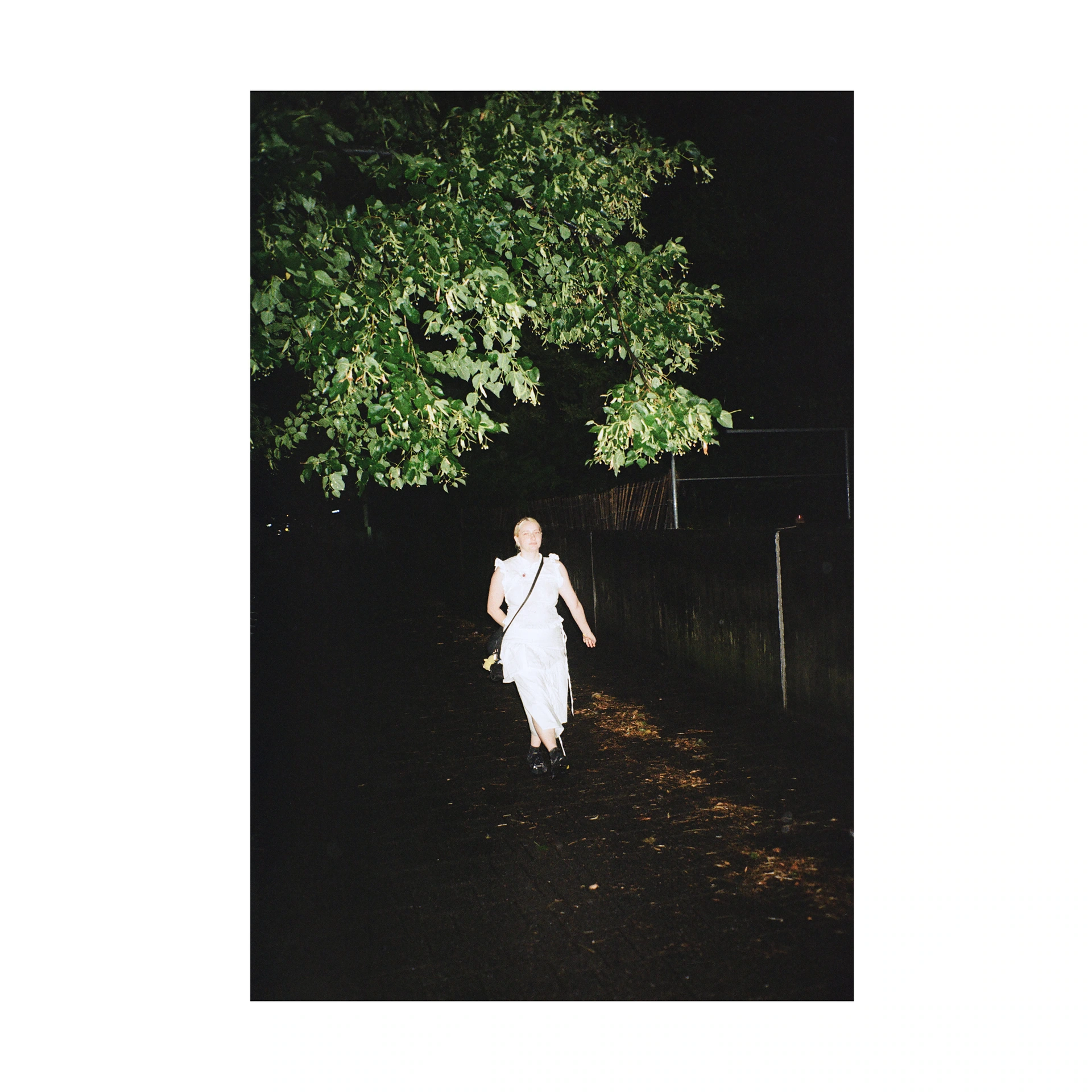 Person dressed in white beneath a tree at night