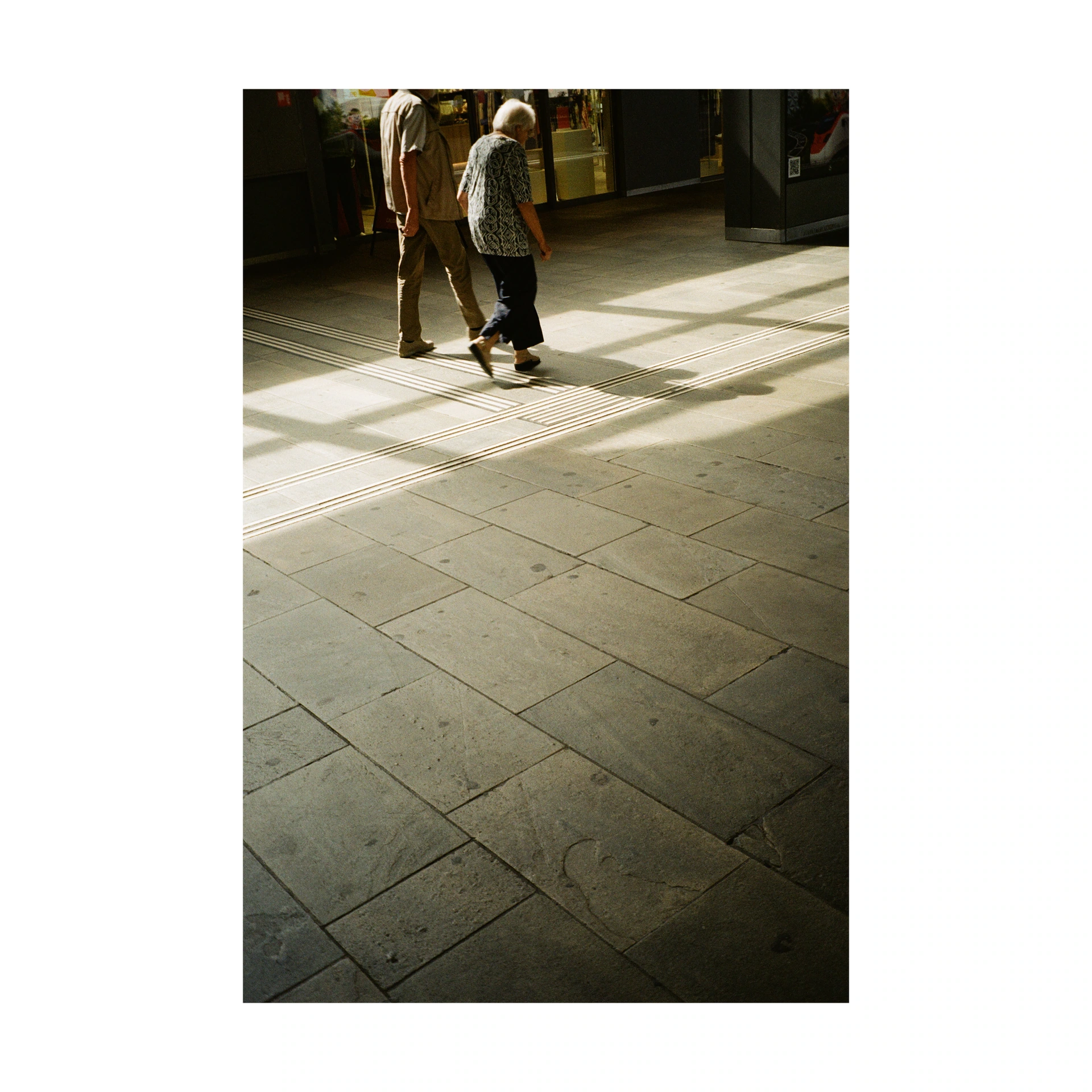 Two people crossing a room with sunlight on the floor