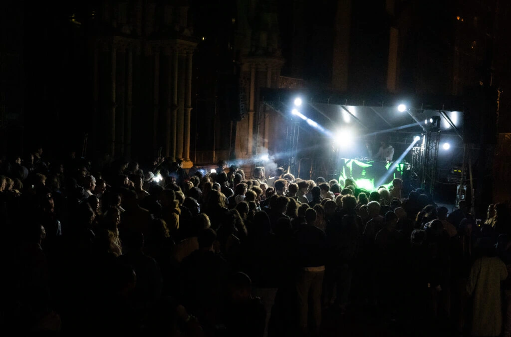 A concert stage and audience under beams of light