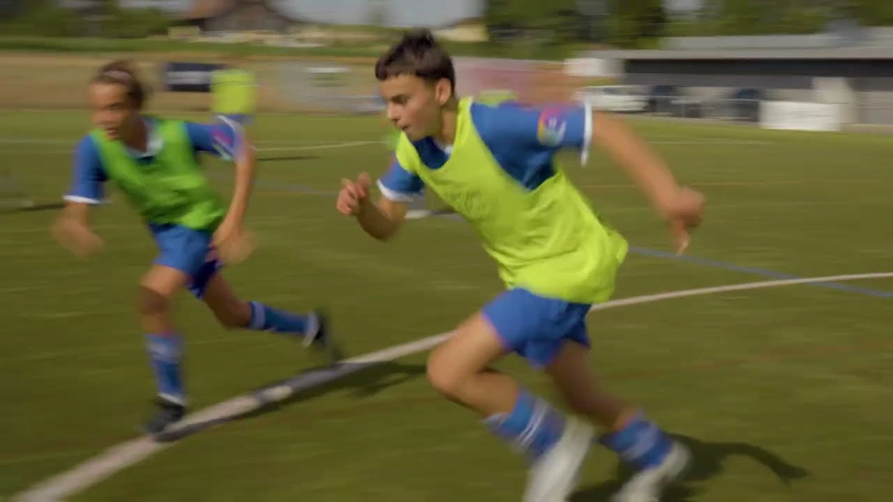 Athletes wearing green training bibs during a running drill